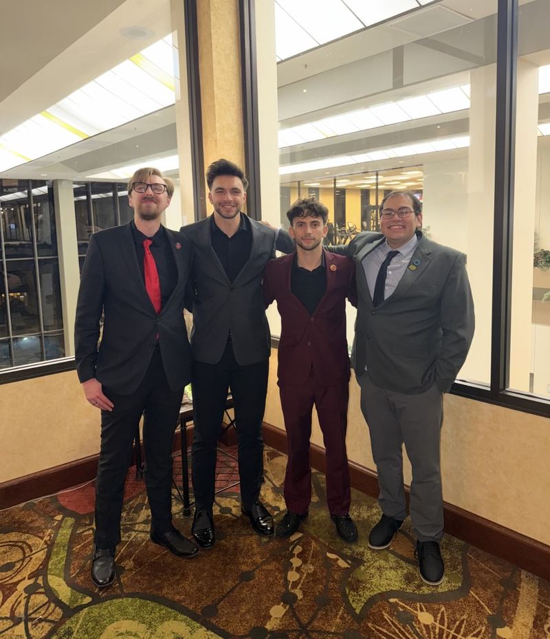 Four LY Marketing team members in suits at a conference venue